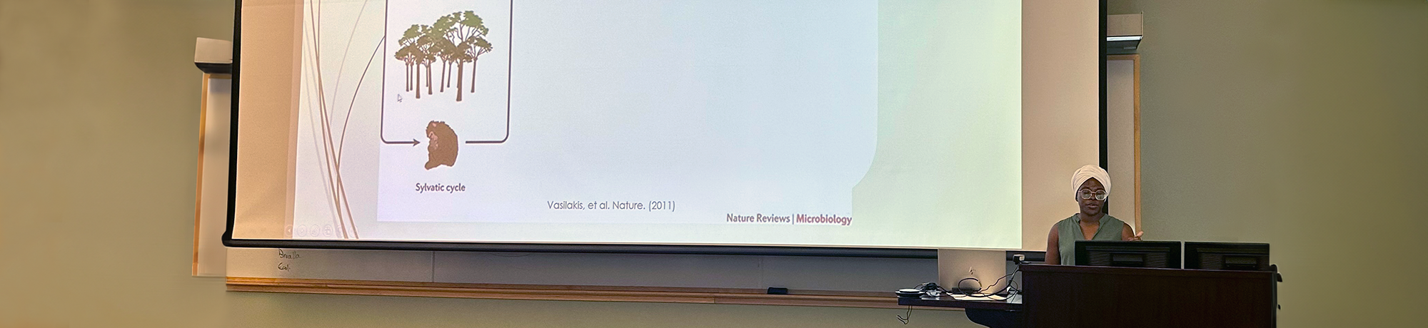 A trainee standing at a podium in front of a slide projected on a screen.